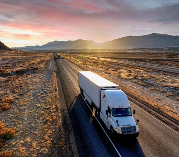 Truck on isolated road with sunset backdrop